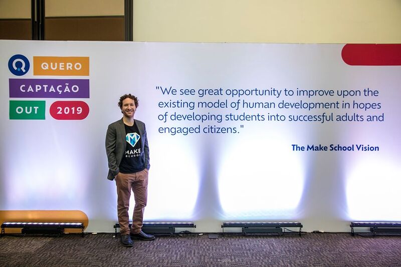 Jeremy Rossmann, da Make School no evento Quero Captação 2019 em frente a um banner com uma frase dele.