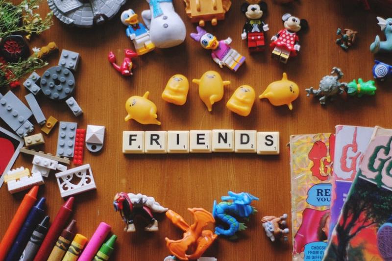 Letras F, R, I, E, N, D, S ao centro em peças de brinquedo representado a palavra "Friends". Brinquedos ao redor. 